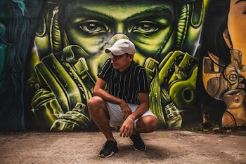 Photo of Man Squat Posing In Front of Graffiti Wall