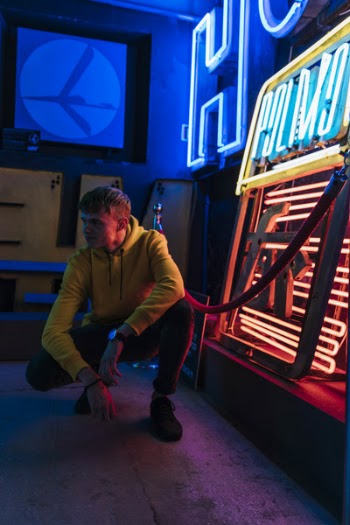 Photo of Man Squatting Beside Neon Sign