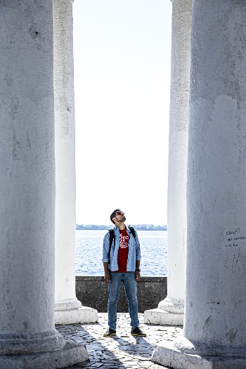 Photo of Man Standing Between White Pillars 