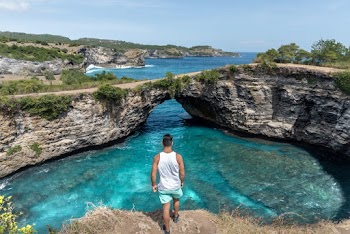 Photo of Man Standing on Cliff Near Lagoon