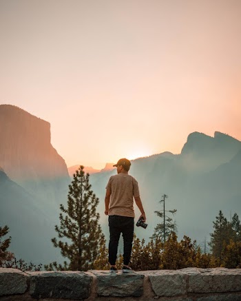 Photo of Man Standing on Concrete Wall While Holding Digital Camera