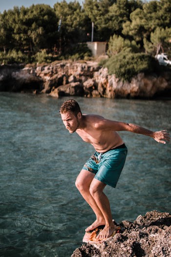 Photo of Man Standing on Rock Cliff in Front