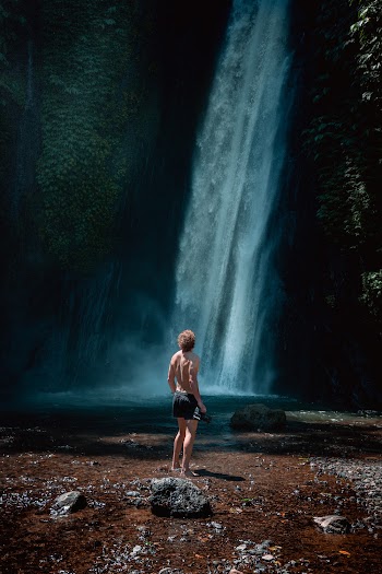 Photo of Man Standing on Rocks Near Waterfalls