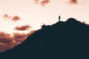 photo of man standing on top of mountain