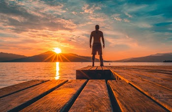 Photo of Man Standing on Wooden Planks Near Sea