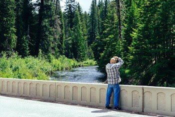 Photo of Man Standing While Taking Picture of Trees and River