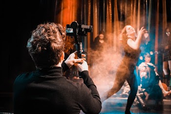 Photo of Man Taking Picture of Woman Dancing on Stage
