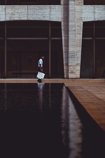 Photo of Man Walking Near Glass Wall Building