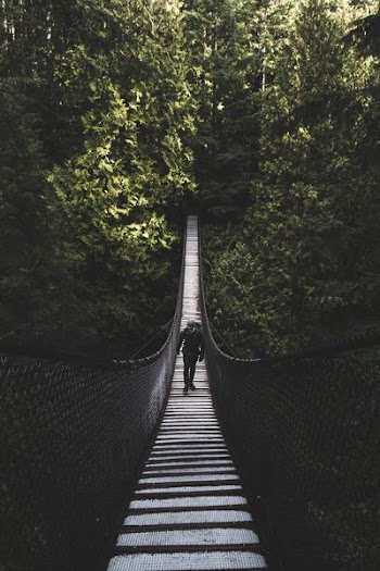 photo of man walking of foot bridge