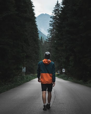 Photo of Man Walking on Road Near Trees