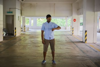 Photo of Man Wearing a Blue Shirt and Brown Shorts Looking at His Watch