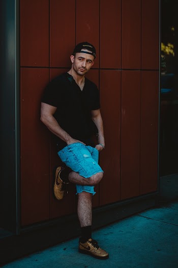 Photo of Man Wearing Black T-Shirt Leaning on Wall