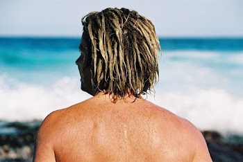 Photo of Man Wearing Blonde Dreadlocks Standing in Front of Seashore