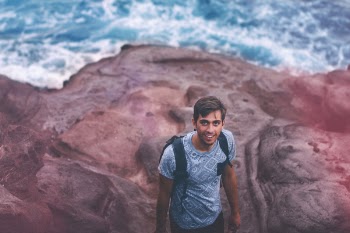 Photo Of Man Wearing Blue Shirt And Backpack Near Ocean