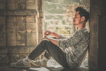 Photo of Man Wearing Gray Sweater and Track Pants Leaning on Wall
