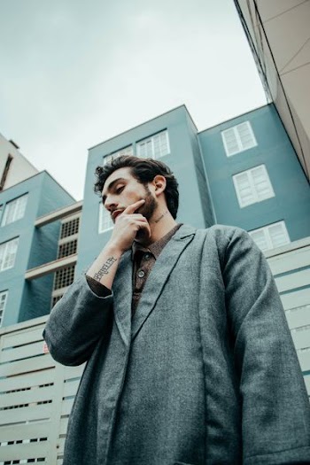 photo of man wearing heather-gray coat resting right hand on chin