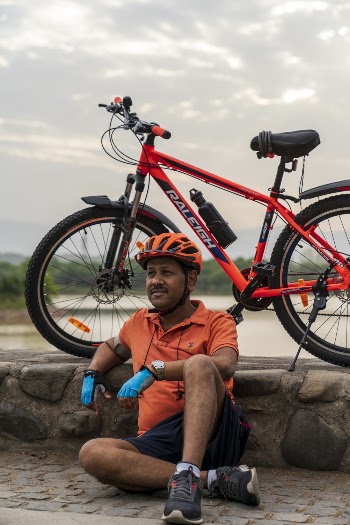 Photo of Man Wearing Orange Polo Shirt Sitting Beside His Bike