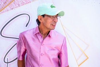 Photo of Man Wearing Pink Button-up Shirt and Green Lacoste Cap Looking Away