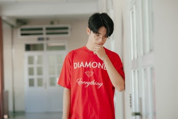 Photo of Man Wearing Red Crew-neck T-Shirt Holding His Chin While Looking Down