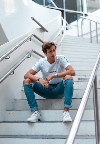 Photo of Man Wearing White Crew-neck T-shirt and Jeans Sitting on Stairs