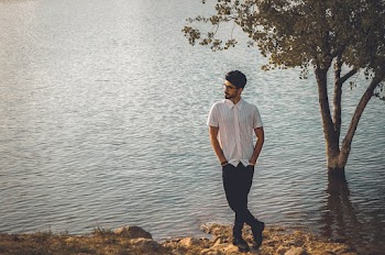 Photo of Man With His Hands in His Pocket Posing Beside Body of Water Looking Away