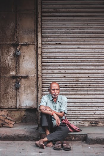 Photo Of Old Man Sitting On Sidewalk