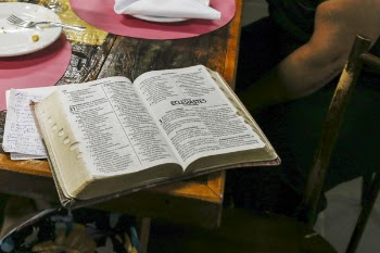 Photo of Opened Bible Book on Brown Table
