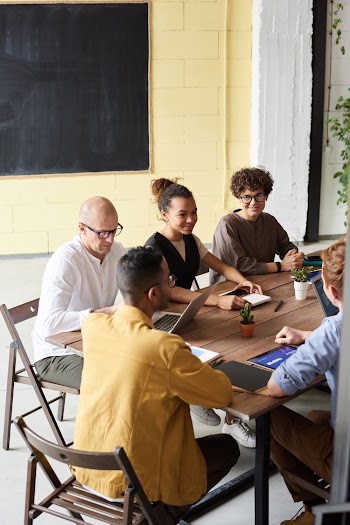 Photo Of People Leaning On Wooden Table