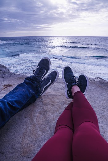 Photo Of People Sitting On Cliff Near Ocean