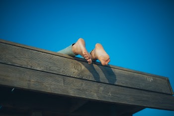 Photo of Person's Feet on Wooden Roof