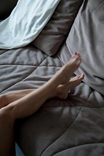 Photo of Person's Legs on a Grey Couch