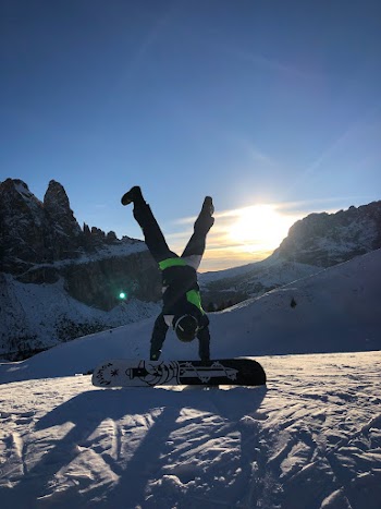Photo of Person Doing Handstand Near Snowboard