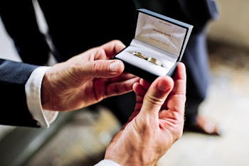 Photo of Person Holding a Black and White Case with Two Gold Rings 