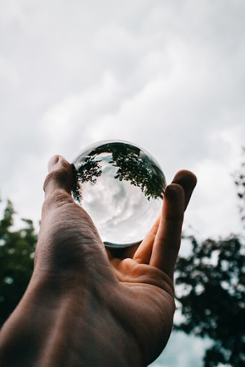 Photo of Person Holding Clear Glass Ball