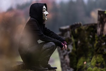 Photo of Person in Black Hoodie and White Mask