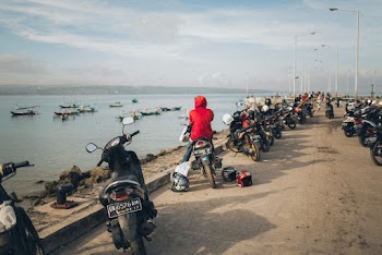 Photo of Person in Red Jacket Sitting on Motorcycle Near Ocean