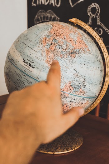 Photo of Person Pointing at Globe
