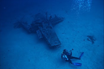 Photo of Person Scuba Diving Near Wreckage