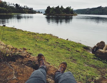 Photo of Person Sitting on Ground Near River