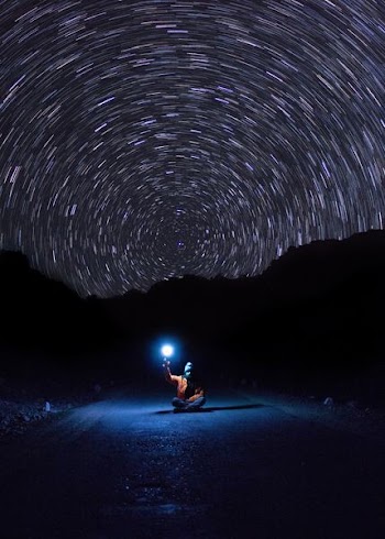 photo of person sitting on pave road holding light