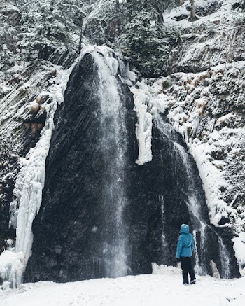 Photo Of Person Standing In Front Of Huge Rock