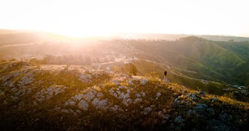 Photo of Person Standing on Rock Near Cliff Edge