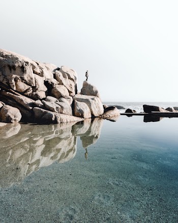 Photo Of Person Standing On Top Of Rock