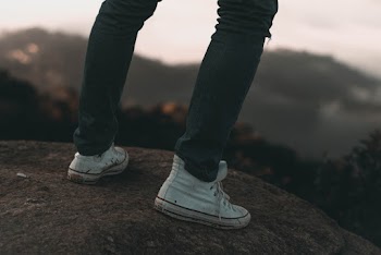 Photo Of Person Standing On Top Of Rock