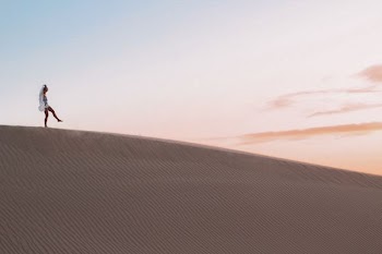 photo of person walking along desert