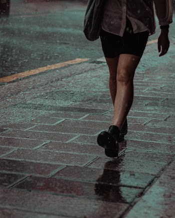 Photo of Person Walking on Pavement While Raining
