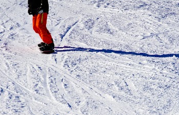 Photo of Person Wearing Black Top and Orange Pants Riding Snowboard