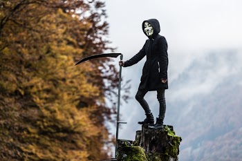 Photo of Person Wearing Guy Fawkes Mask While Holding Scythe
