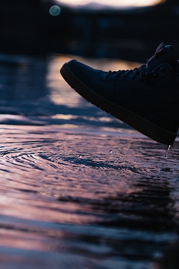 Photo of Person Wearing Shoe Near Body of Water