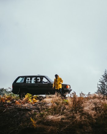 Photo of Person Wearing Yellow Raincoat Standing Near Gray SUV